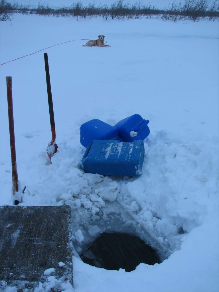 First, hack a hole into the river ice with a pickax. Then cover it with plywood so it won't freeze over again.